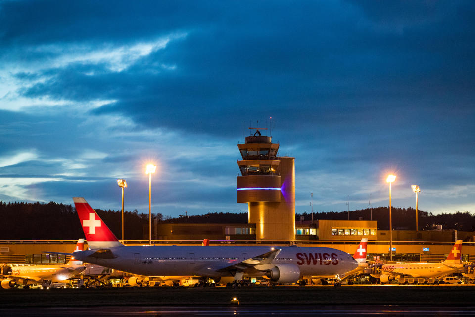 Zurich, Switzerland - March 13, 2018: Overview of Zurich Airport with a Swiss International Air Lines Boeing 777-300ER in front of the control tower. Zurich Airport is the largest international airport of Switzerland and the principal hub of Swiss International Air Lines.