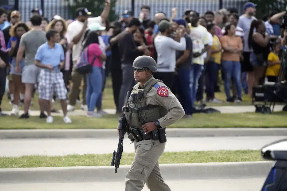 A law enforcement officer walks as people are evacuated from a shopping center where a shooting occurred Saturday, May 6, 2023, in Allen, Texas. (AP Photo/LM Otero)