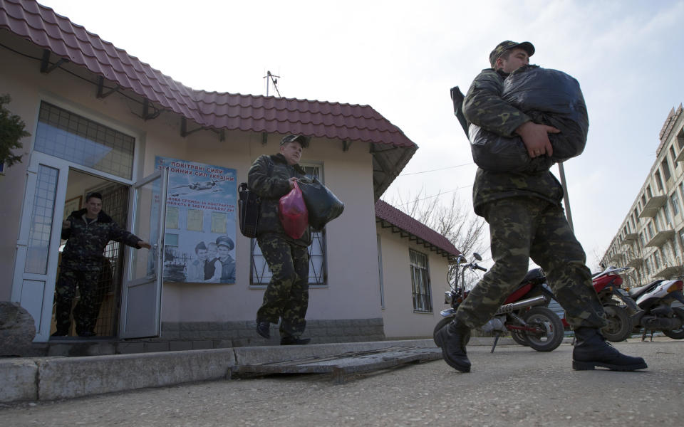 Ukrainian air force officers walk with their bags at the Belbek airbase, outside Sevastopol, Crimea, on Thursday, March 20, 2014. With thousands of Ukrainian soldiers and sailors trapped on military bases, surrounded by heavily armed Russian forces and pro-Russia militia, the Kiev government said it was drawing up plans to evacuate its outnumbered troops from Crimea back to the mainland and would seek U.N. support to turn the peninsula into a demilitarized zone. (AP Photo/Ivan Sekretarev)