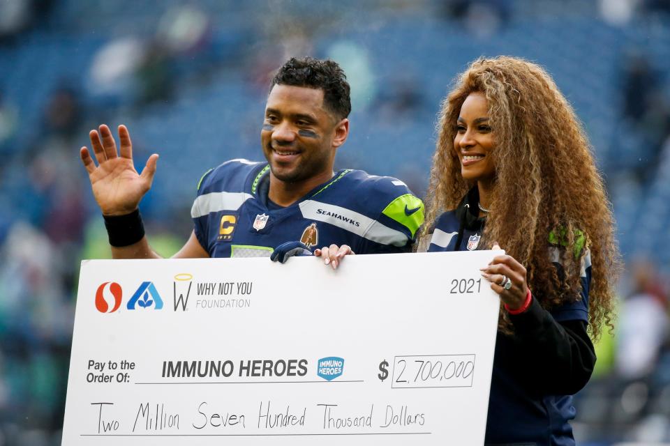 Seattle Seahawks quarterback Russell Wilson and wife Ciara pose for a photo with a charitable donation check during a ceremony before a game against the Detroit Lions at Lumen Field in Seattle on Jan. 2, 2022.