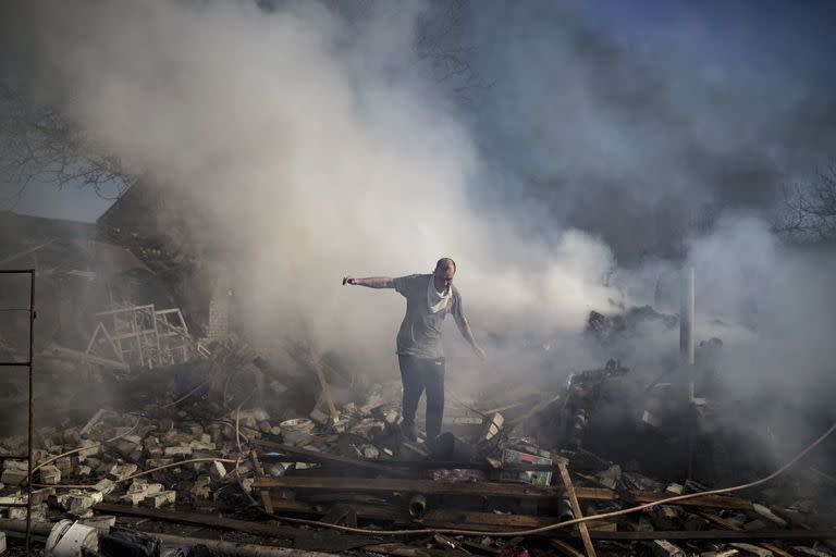 Un vecino camina sobre los escombros de una casa en llamas, destruida tras un ataque ruso en Kharkiv, Ucrania, el jueves 24 de marzo de 2022.