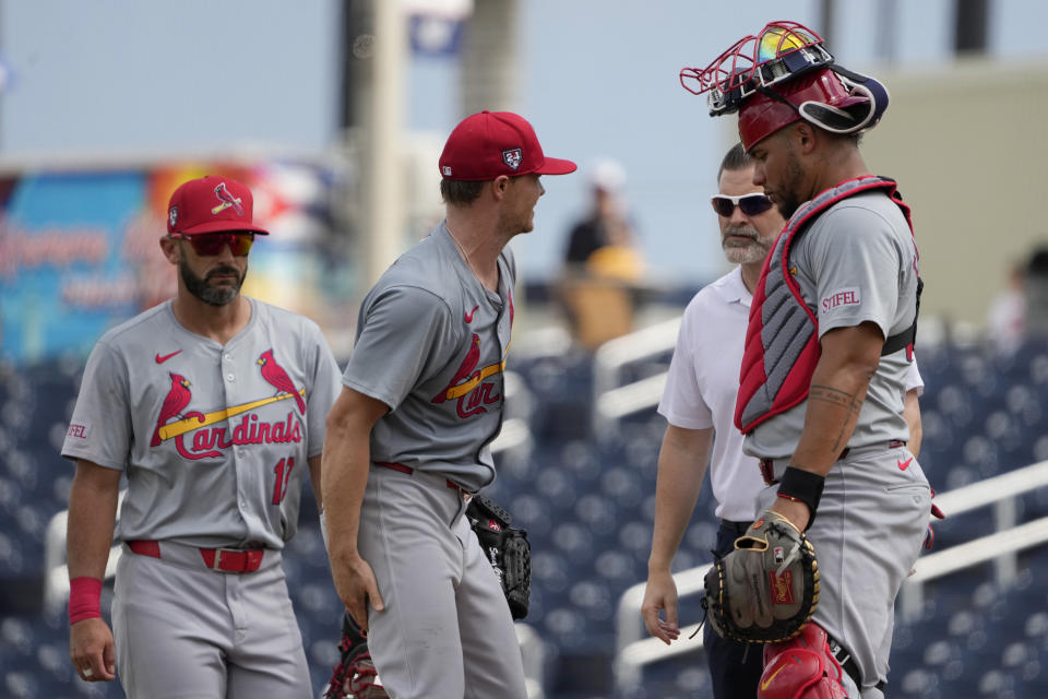 St. Louis Cardinals starting pitcher Sonny Gray, second from left, rubs his leg as he talks on the mound with catcher Willson Contreras, right, trainer Adam Olsen and first baseman Matt Carpenter, left, before being removed during the second inning of a spring training baseball game against the Washington Nationals Monday, March 4, 2024, in West Palm Beach, Fla. The team announced that Gray was removed due to tightness in his right hamstring. (AP Photo/Jeff Roberson)