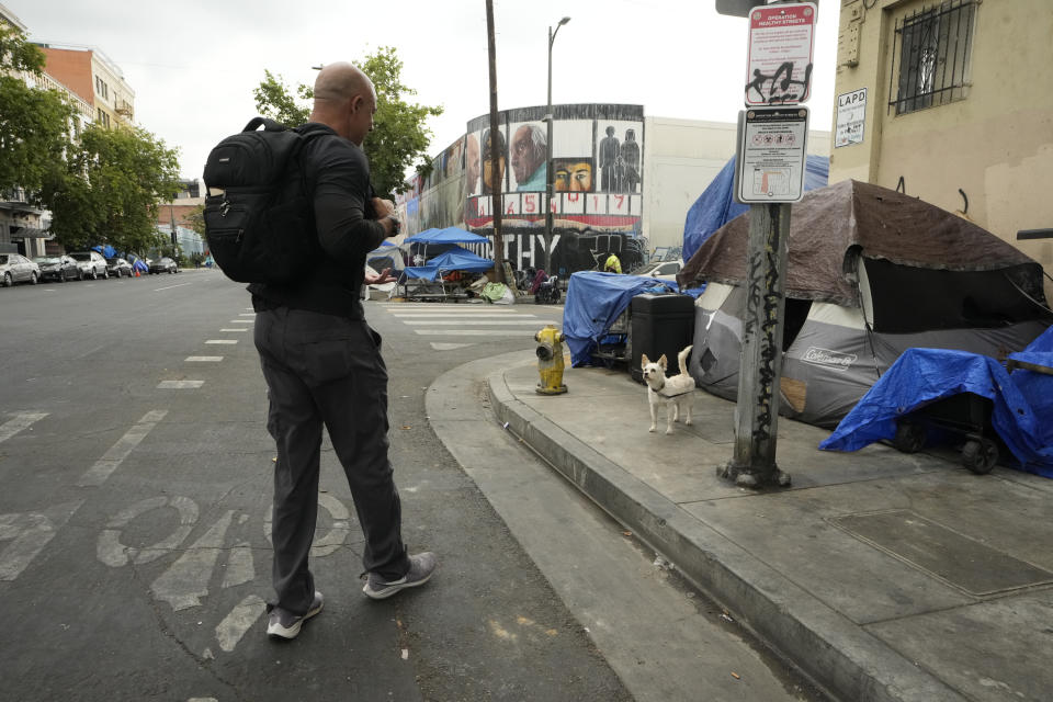 Dr. Kwane Stewart is greeted by the dog Popcorn in the Skid Row area of Los Angeles on Wednesday, June 7, 2023. “The Street Vet,” as Stewart is known, has been supporting California's homeless population and their pets for almost a decade. (AP Photo/Damian Dovarganes)