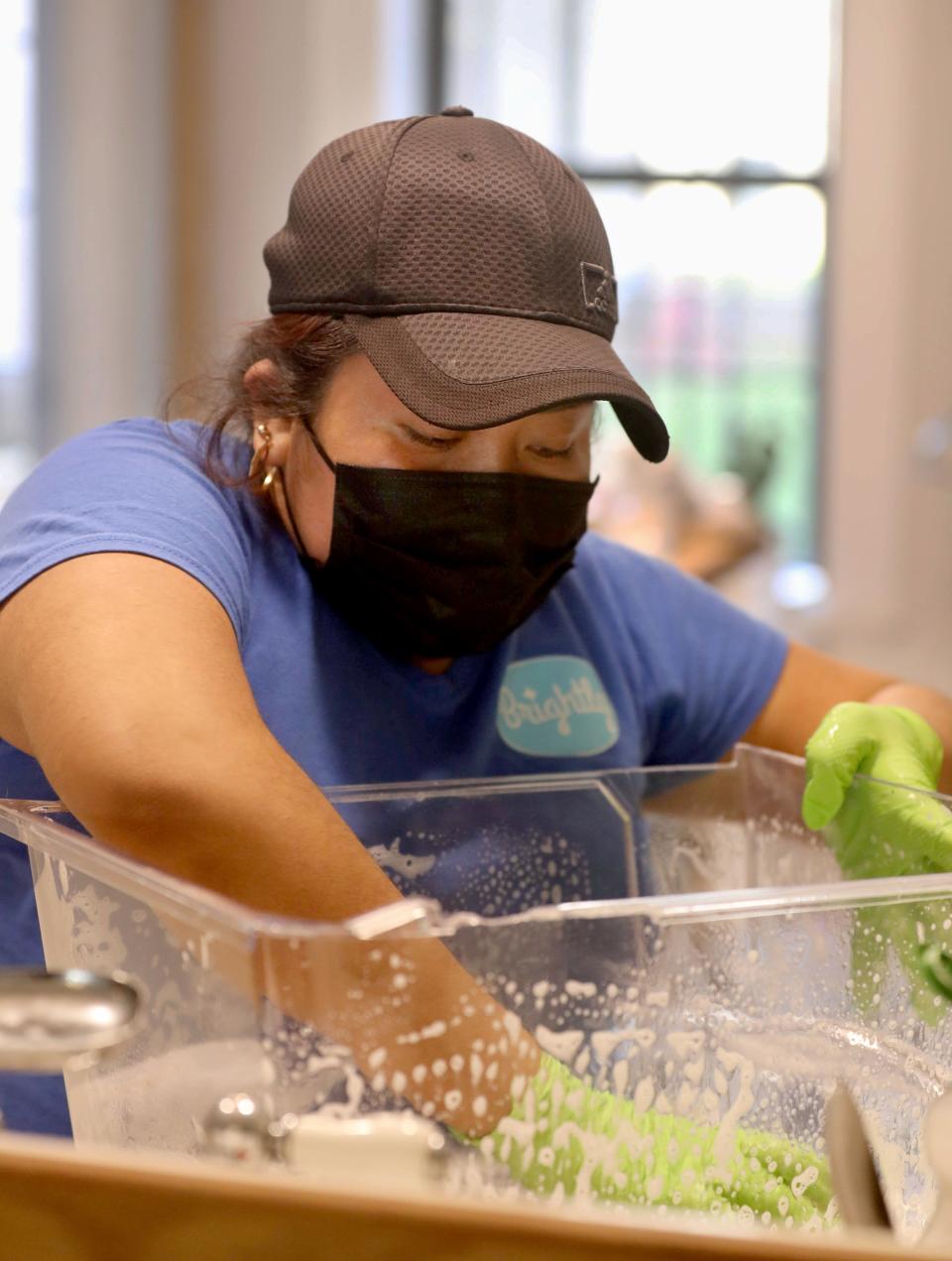Natavidad Aguilar, a member of the Brightly Cleaning Cooperative, washes a refrigerator container while cleaning a home in Brooklyn March 22, 2022. Brightly is a franchise of worker-owned cooperatives that offers eco-friendly cleaning residential and commercial cleaning services.