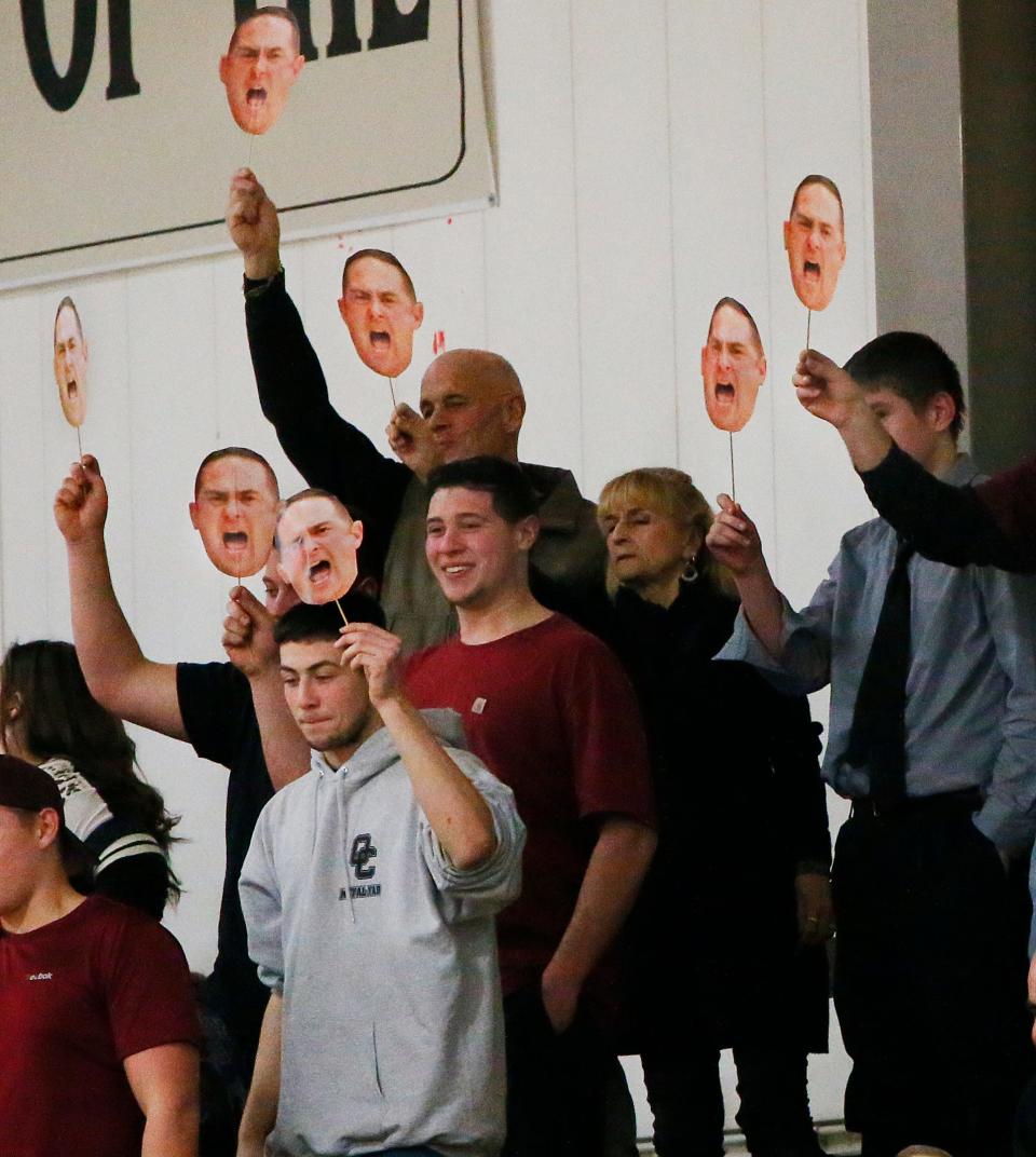 Old Colony fans hold picture cutouts of their favorite head basketball coach, Matt Trahan.