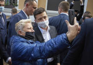 FILE In this file photo taken on Wednesday, June 3, 2020, A woman in a face mask to protect against coronavirus, takes a selfie with Ukrainian President Volodymyr Zelenskiy during his working visit in the town of Khmelnitsky, central Ukraine. Ukrainians are heading to the polls on Sunday, Oct. 25, 2020 to cast ballots in local elections seen as a key test for President Volodymyr Zelenskiy. Zelenskiy, a popular comedian without prior political experience, was elected by a landslide in April 2019 on promises to end fighting with Russia-backed separatists in eastern Ukraine, uproot endemic corruption and shore up a worsening economy. (Ukrainian Presidential Press Office via AP, File)