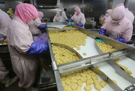 Employees work at a production line prior to a seizure conducted by officers from the Shanghai Food and Drug Administration, at the Husi Food factory in Shanghai, July 20, 2014. REUTERS/Stringer