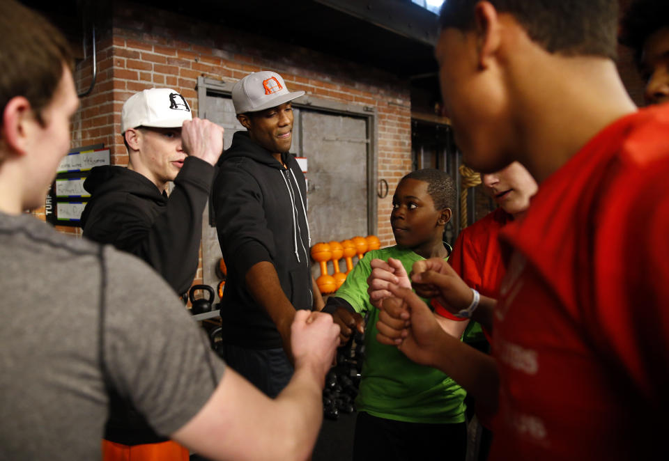 BOSTON - MARCH 22: Boys & Girls Clubs of Greater Boston members huddle with George Foreman III, center, and boxing trainer Shane Jordan, 21, of Brockton, Mass., after a work out session led by Jordan inside the high-end gym The Club By George Foreman III in the South Boston neighborhood on March 22, 2015. (Photo by Jessica Rinaldi/The Boston Globe via Getty Images)