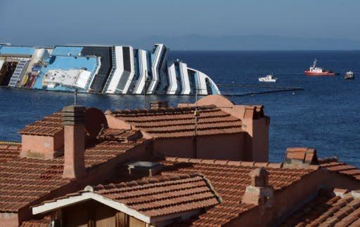 Italian coast guard ships patrol near the stranded Costa Concordia cruise ship, at Giglio Porto, on July 13. For as little as 10 euros, visitors can take a day trip to see the ghostly white wreck of the 114,500-tonne luxury cruise liner, lying on its side after running aground off Giglio Island on January 13, killing 32 people