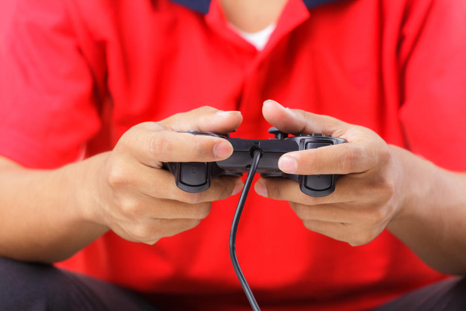 Person in red shirt holding video game controller in hands.