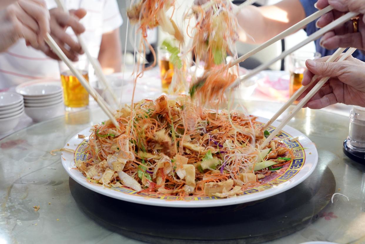 Tossing yusheng at a Chinese New Year "lohei". (Photo: Getty Images)