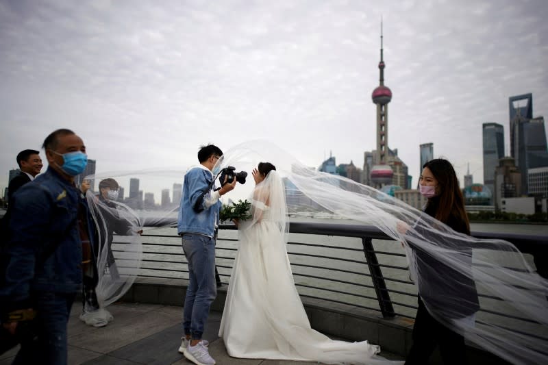 Staff members wearing face masks help a couple with their wedding photo shoot in Shanghai