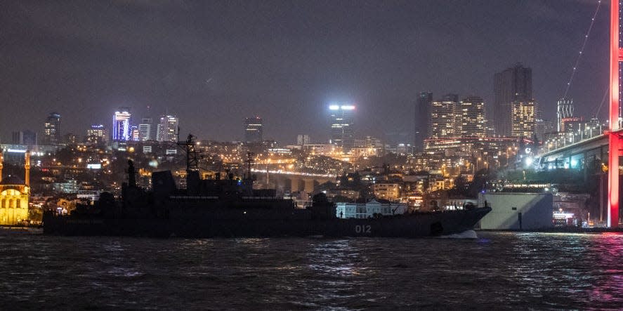 A Russian landing vessel sailing at night against the background of Istanbul buildings.