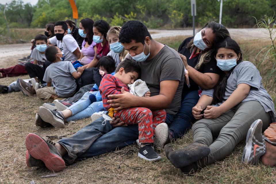 A Guatemalan family waits with fellow immigrants to board a U.S. Customs and Border Protection bus to a processing center after crossing the border from Mexico on April 13 in La Joya, Texas. Many of the migrants entering the United States seeking asylum are being expelled into Mexico under Title 42, though unaccompanied children and some families are exempt from the policy.