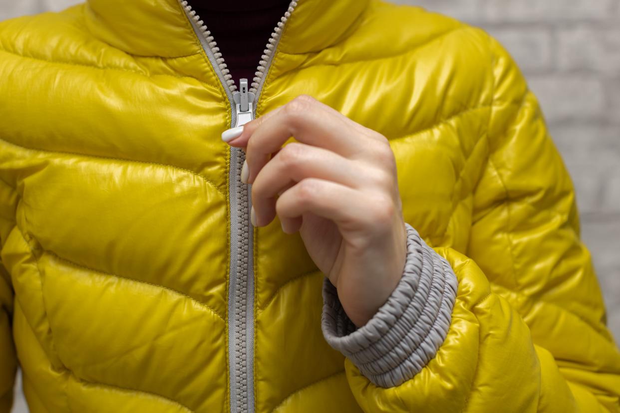 a woman zips up her jacket around her throat. High quality photo