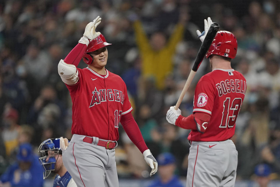 Los Angeles Angels' Shohei Ohtani, left, is greeted at the plate by Phil Gosselin (13) after Ohtani hit a solo home run during the first inning of a baseball game against the Seattle Mariners, Sunday, Oct. 3, 2021, in Seattle. (AP Photo/Ted S. Warren)