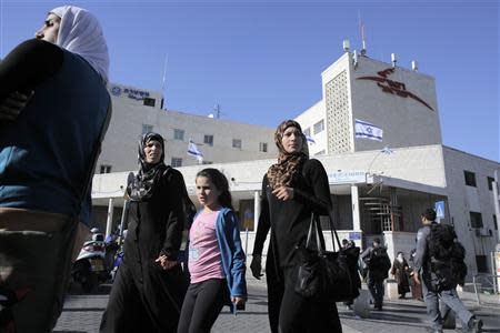 Palestinians walk past a post office building in East Jerusalem April 29, 2014. REUTERS/Ammar Awad