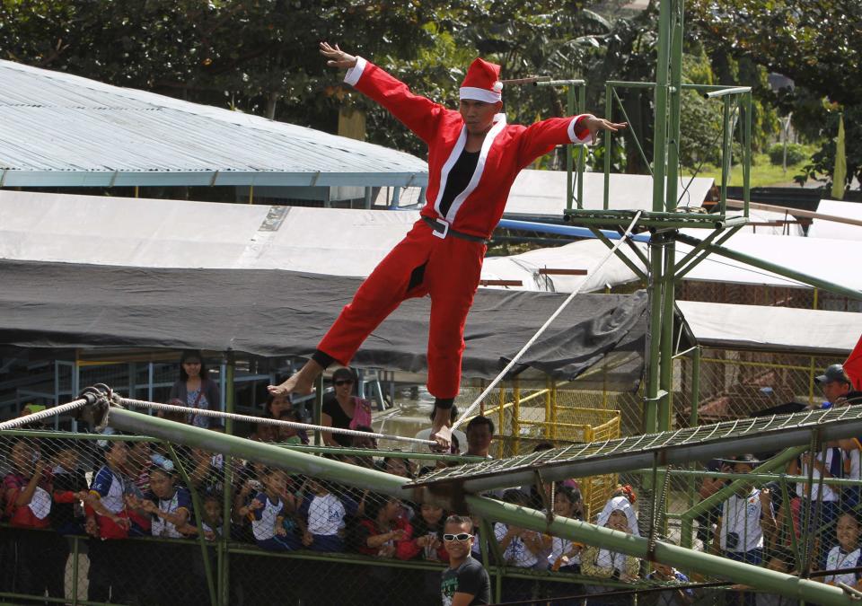 A man walks on a tight rope over live crocodiles while wearing a Santa Claus costume as part of performances for the Yuletide season at a crocodile farm in Pasay city