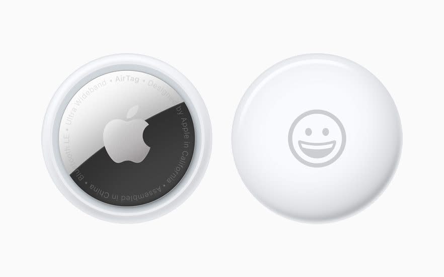 Two round white metal and plastic pucks are shown on a white background, each one with a different side visible. On one, an Apple logo; on the other, a smiling face emoji - Apple