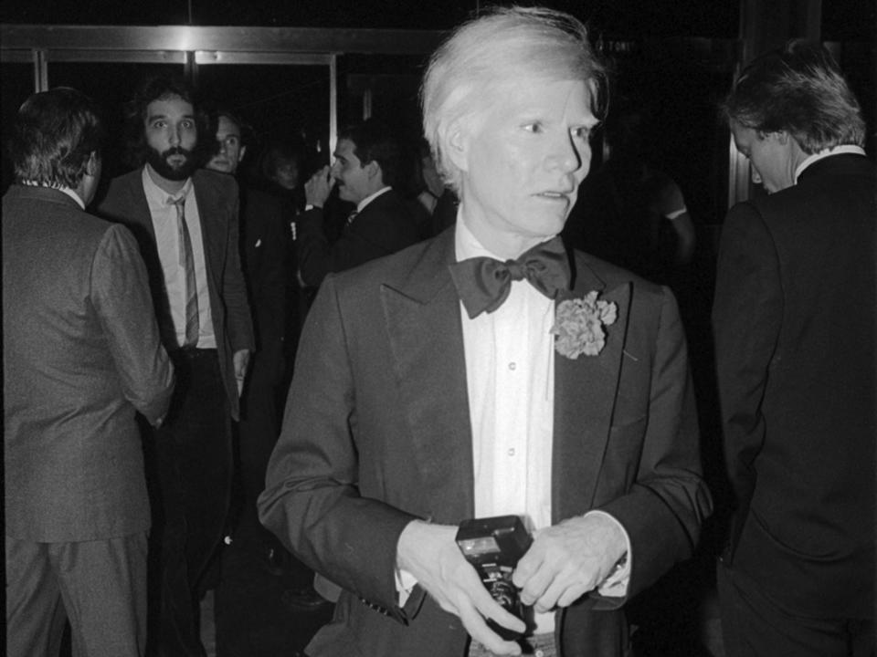 American Pop artist Andy Warhol carries a camera as he arrives at Studio 54, New York, New York, October 9, 1979. (Photo by Allan Tannenbaum/Getty Images)