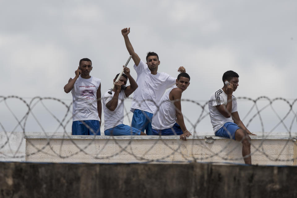 Inmates gesture and talk on cell phones as they stand on the roof of a building amid tension between rival gangs in the Alcacuz prison in Nisia Floresta, near Natal, Brazil, Friday, Jan. 20, 2017. (AP Photo/Felipe Dana)