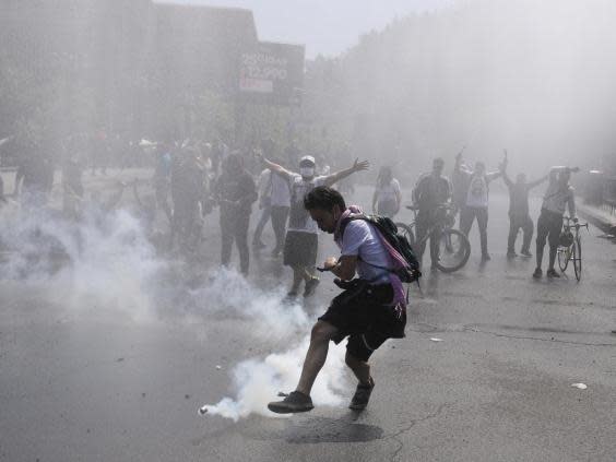 A protester kicks a tear gas canister during clashes in Santiago (AP)