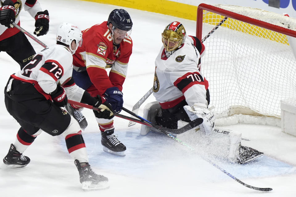 Florida Panthers center Aleksander Barkov (16) attempts a shot against Ottawa Senators goaltender Joonas Korpisalo (70) and defenseman Thomas Chabot (72) during the second period of an NHL hockey game, Tuesday, Feb. 20, 2024, in Sunrise, Fla. (AP Photo/Wilfredo Lee)