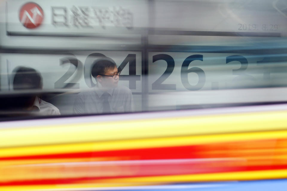 A man stands in front of an electronic stock board showing Japan's Nikkei 225 index as a car passes by at a securities firm in Tokyo Thursday, Aug. 29, 2019. Asian stocks declined Thursday following Wall Street's rebound amid uncertainty about U.S.-Chinese trade tension. (AP Photo/Eugene Hoshiko)