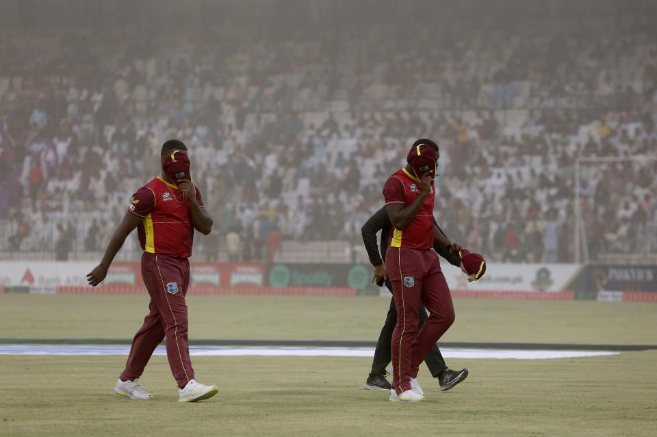 West Indies' players cover their faces as they leave the field due to a dust-storm stop in the play during the third one-day international cricket match between Pakistan and West Indies at the Multan Cricket Stadium, in Multan, Pakistan, Sunday, June 12, 2022. (AP Photo/Anjum Naveed)