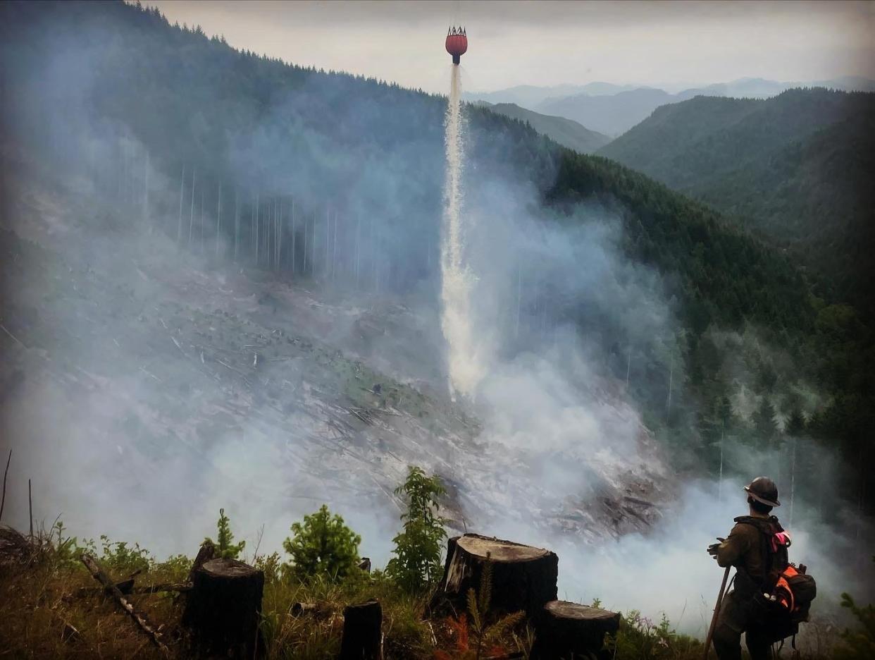 A firefighter watches as water is dropped on a hot spot on the 7K Fire near Veneta, Oregon.