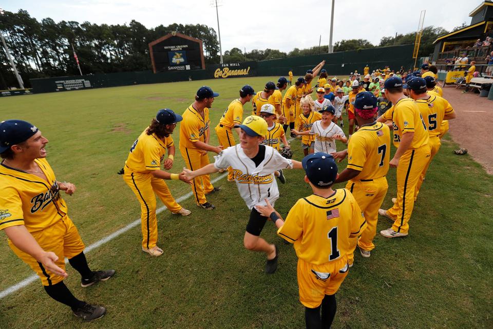 Summer campers get high-fives from the Savannah Bananas before the start of a recent home game at Grayson Stadium.