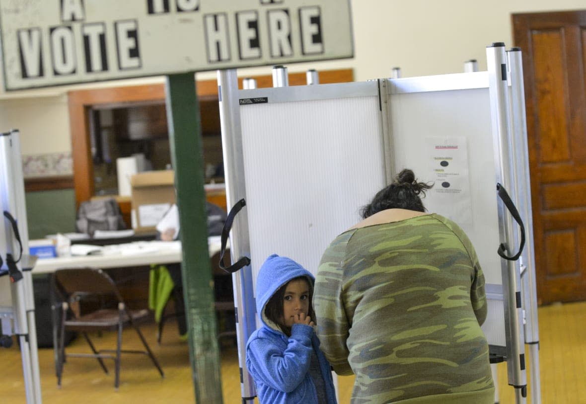 Nora Eames, 6, of Bellows Falls, keeps close to her mother, Zoe, as Zoe fills out her ballot at a polling station in Rockingham, Vt., during the midterm elections on Tuesday, Nov. 8, 2022. (Kristopher Radder/The Brattleboro Reformer via AP)