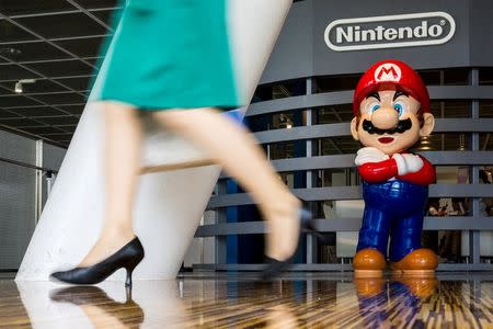 A woman walks past a figure of "Mario", a character in Nintendo's "Mario Bros." video games, at a Nintendo centre in Tokyo July 29, 2015. REUTERS/Thomas Peter/File Photo