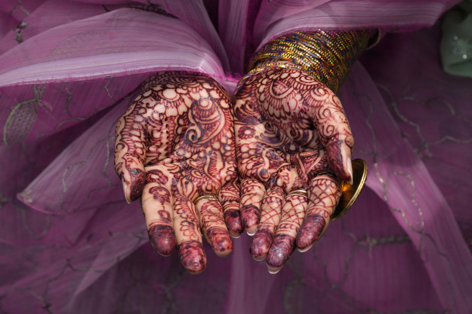 A Muslim woman paints her hands with traditional "henna" as she performs an Eid al-Fitr prayer, marking the end of the fasting month of Ramadan, at historical Badshahi mosque, in Lahore, Pakistan, Saturday, April, 22, 2023. (AP Photo/K.M. Chaudary)