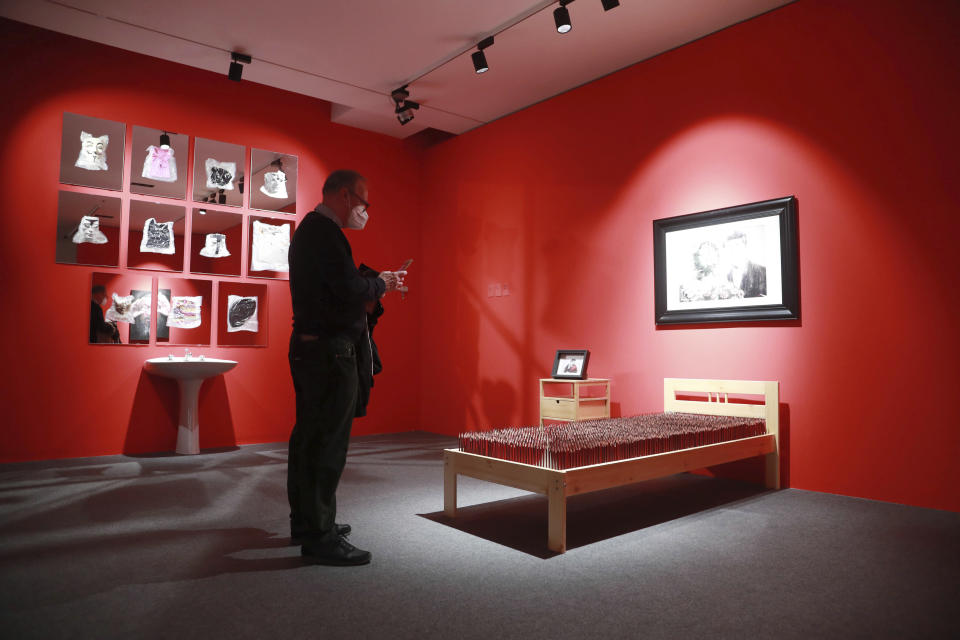 Visitors look at artwork during the opening of artist Badiucao's exhibition in the Santa Giulia Museum, in Brescia, Saturday, Nov. 13, 2021. A provocative exhibit by dissident Chinese artist Badiucao opened Saturday in the industrial northern Italian city of Brescia despite pressure from the Chinese embassy in Rome to cancel it. A letter from the embassy included veiled economic threats, noting Italy’s trade with China, in a bid to prevent the first solo exhibit by Badiucao — the pseudonym used by the artist whose work takes aim at China's policies and human rights record. (AP Photo/Felice Calabro')