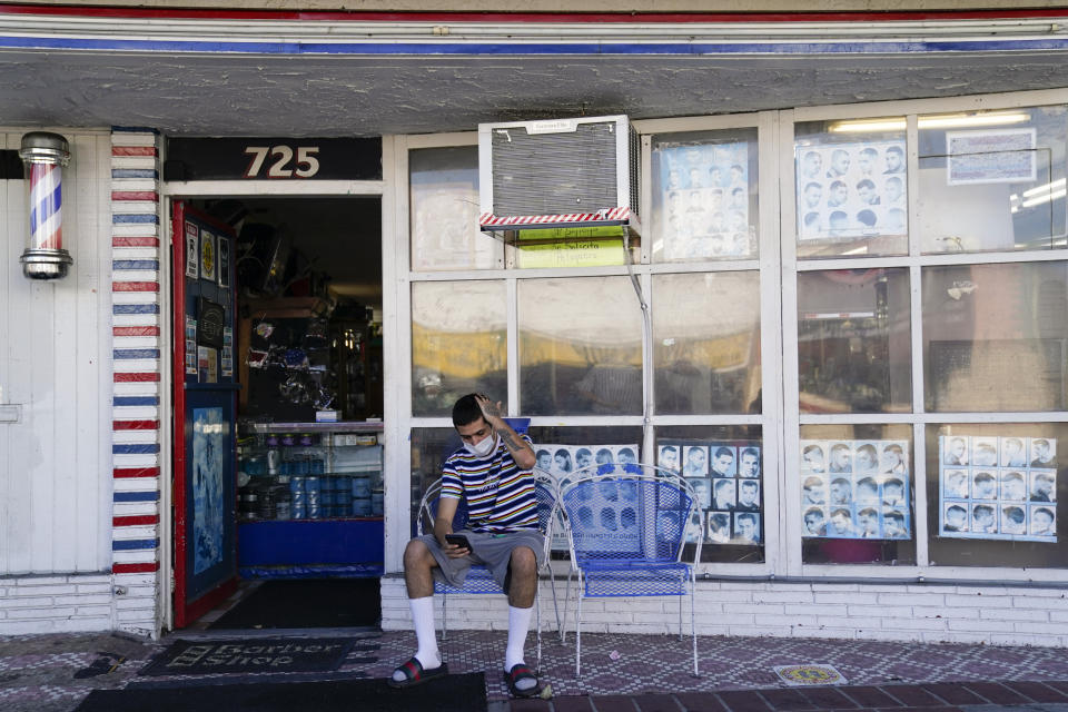 Anthony Milinkovich waits for his turn for a haircut, outside George's Barber Shop on Tuesday, July 14, 2020, in San Pedro, Calif. Gov. Gavin Newsom this week ordered that indoor businesses like salons, barber shops, restaurants, movie theaters, museums and others close due to the spread of COVID-19. (AP Photo/Ashley Landis)