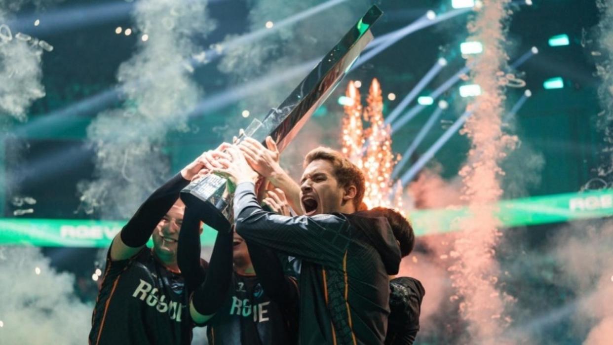 Rogue Esports players lifting a trophy with smoke in the background