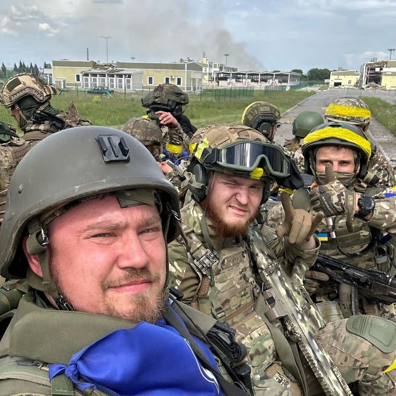 Members of Russian Volunteer Corps pose for a picture atop an armoured vehicle at Graivoron border crossing in Kozinka