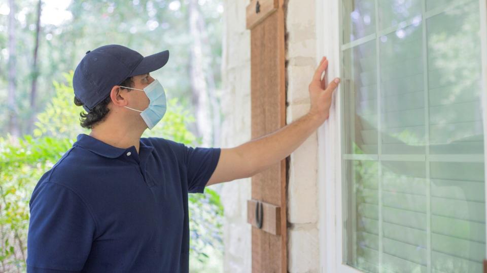 Repairmen, building inspectors, exterminators, engineers, insurance adjusters, or other blue collar workers examine a building/home's exterior walls.