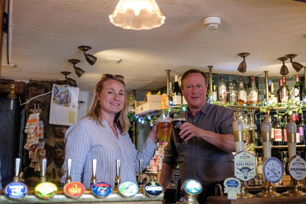 Behind the bar: Meg Powell-Chandler and Lord David Cameron. <i>(Image: Conservatives)</i>