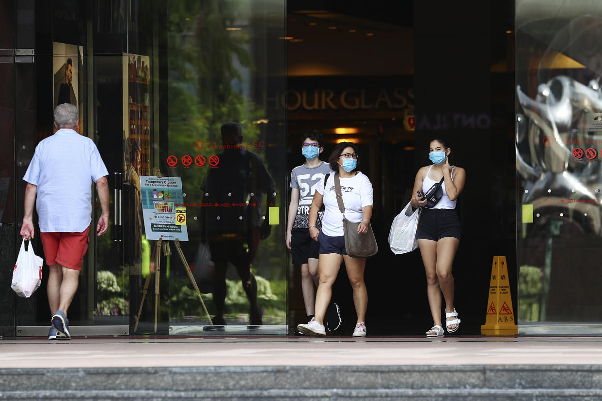 People wearing protective face masks exit a mall along the Orchard Road shopping belt in Singapore. (AP Photo/Yong Teck Lim)