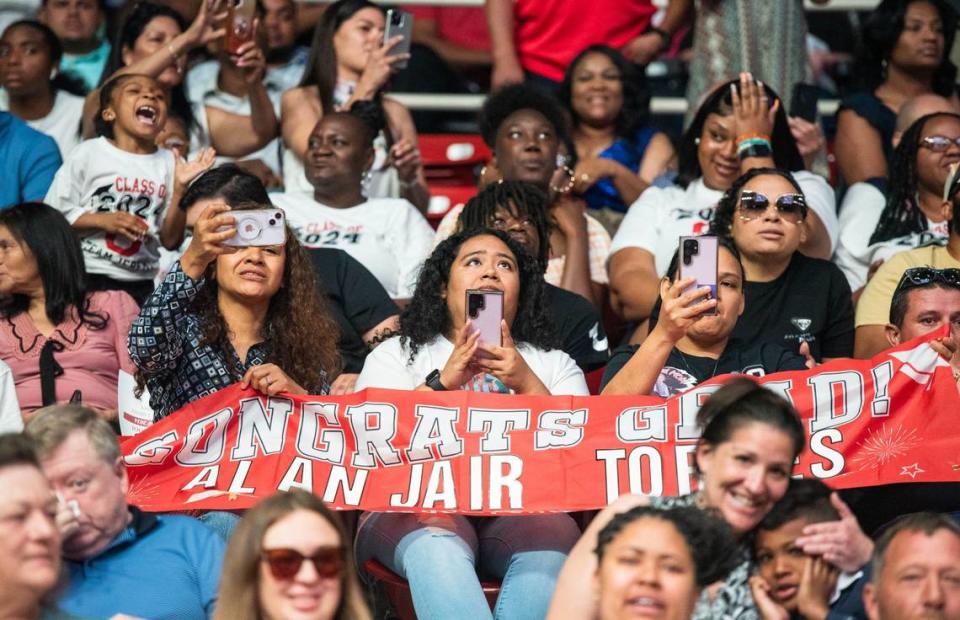 Crowd members show their support for the Olympic High School graduate Alan Jair with a sign as his name is announced at the Bojangles Coliseum in Charlotte on Monday, June 10, 2024.