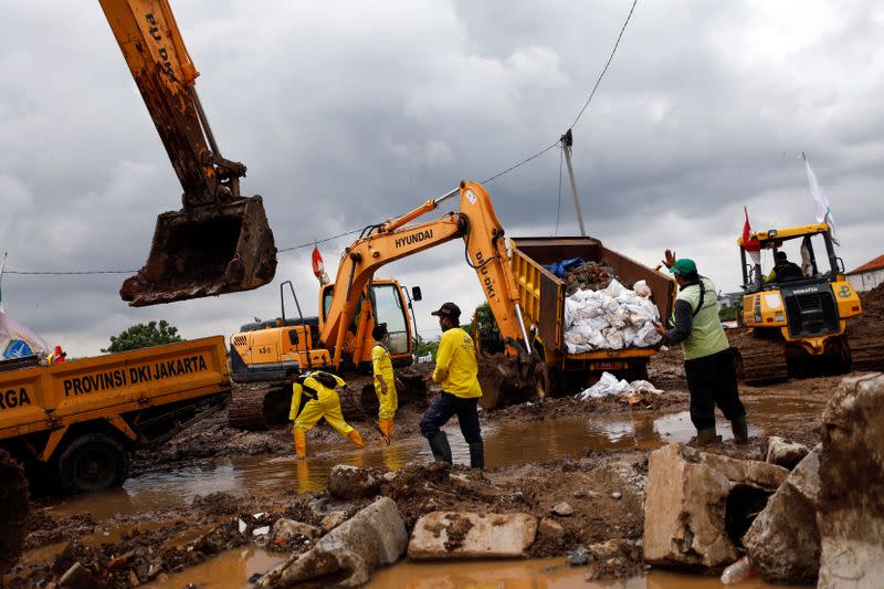 Workers among heavy vehicles work for opening a new cemetery area for the COVID-19 victims in Jakarta