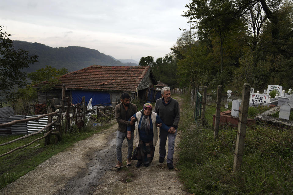 Habibe Ayvaz, 63, receives help to walk after visiting the grave of her son Selcuk Ayvaz, 33, one of the miners killed in a coal mine explosion, in Amasra, in the Black Sea coastal province of Bartin, Turkey, Sunday, Oct. 16, 2022. (AP Photo/Khalil Hamra)