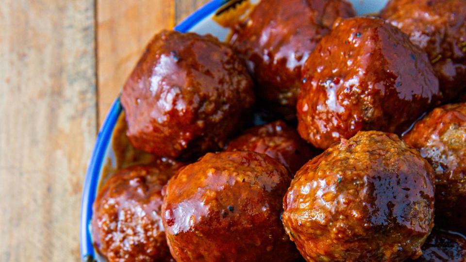 grape jelly meatballs in a blue bowl on a wooden background