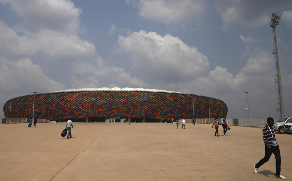 People walking at a newly build Olembe stadium in Yaounde, Cameroon, Saturday, Jan. 8, 2022. The African Cup of Nations takes place in Cameroon and starts on Sunday, Jan. 9. (AP Photo/Themba Hadebe)