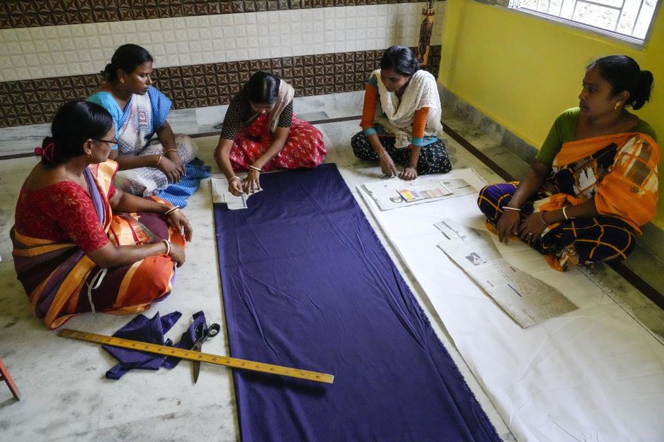 Kakali Halder, second left, watch a session of school uniform cutting in Mathurapur, South 24 Pargana district, India, Monday, March 27, 2023. She and several hundred fellow seamstresses at Mathurapur Sanghati Swayamber Sangha, a group that make clothing items and share the proceeds between them, have worked with the stress of trying to get orders out when they can't rely on the electricity. (AP Photo/Bikas Das)