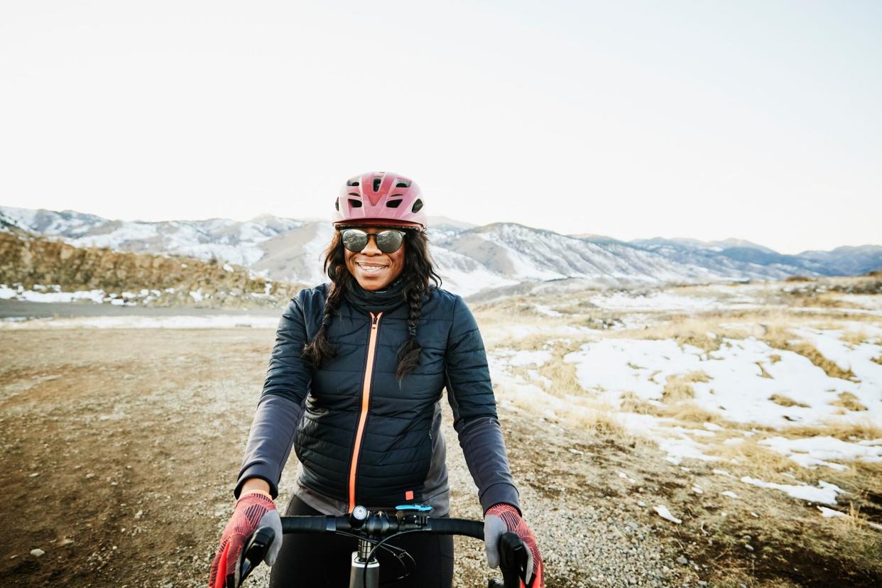 Portrait of smiling female cyclist riding gravel bike at sunset on winter evening