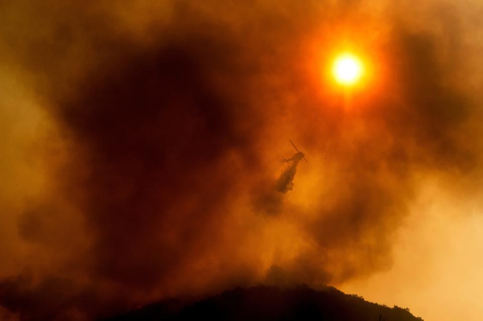 In this Monday, Aug. 17, 2020, file photo, a helicopter drops water while battling the River Fire in Salinas, Calif. According to data released on Tuesday, May 4, 2021, the new United States normal is not just hotter, but wetter in the eastern and central parts of the nation and considerably drier in the West than just a decade earlier.