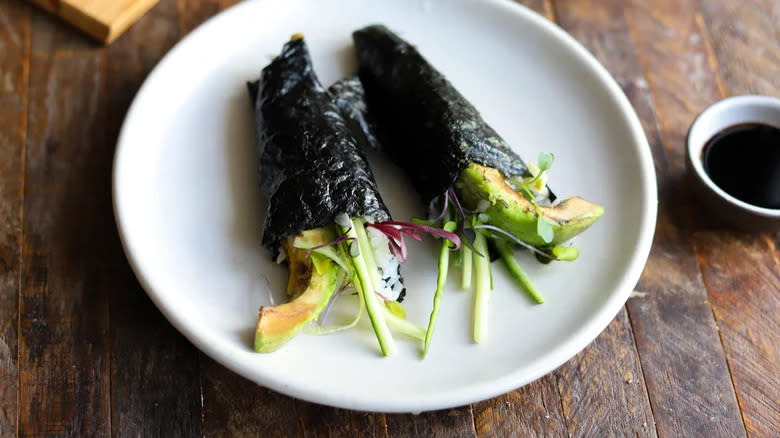 Two plated avocado hand rolls